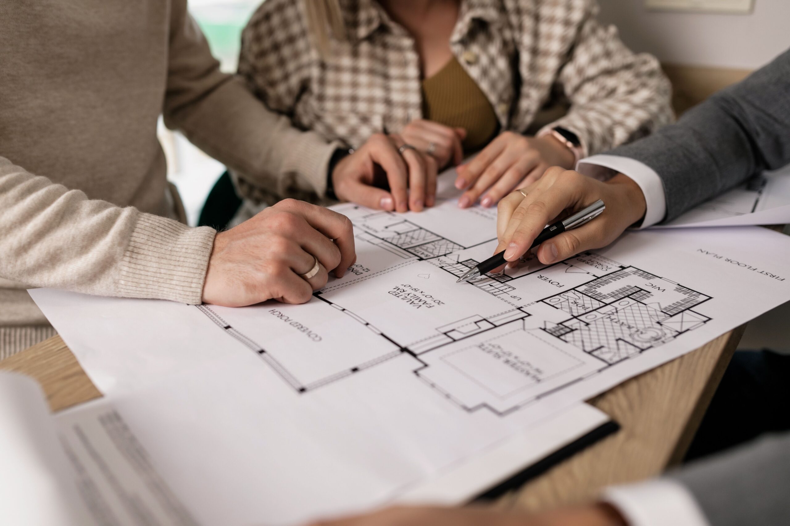 Servicios Group examining house floor plans with a real estate agent, highlighting home buying process.